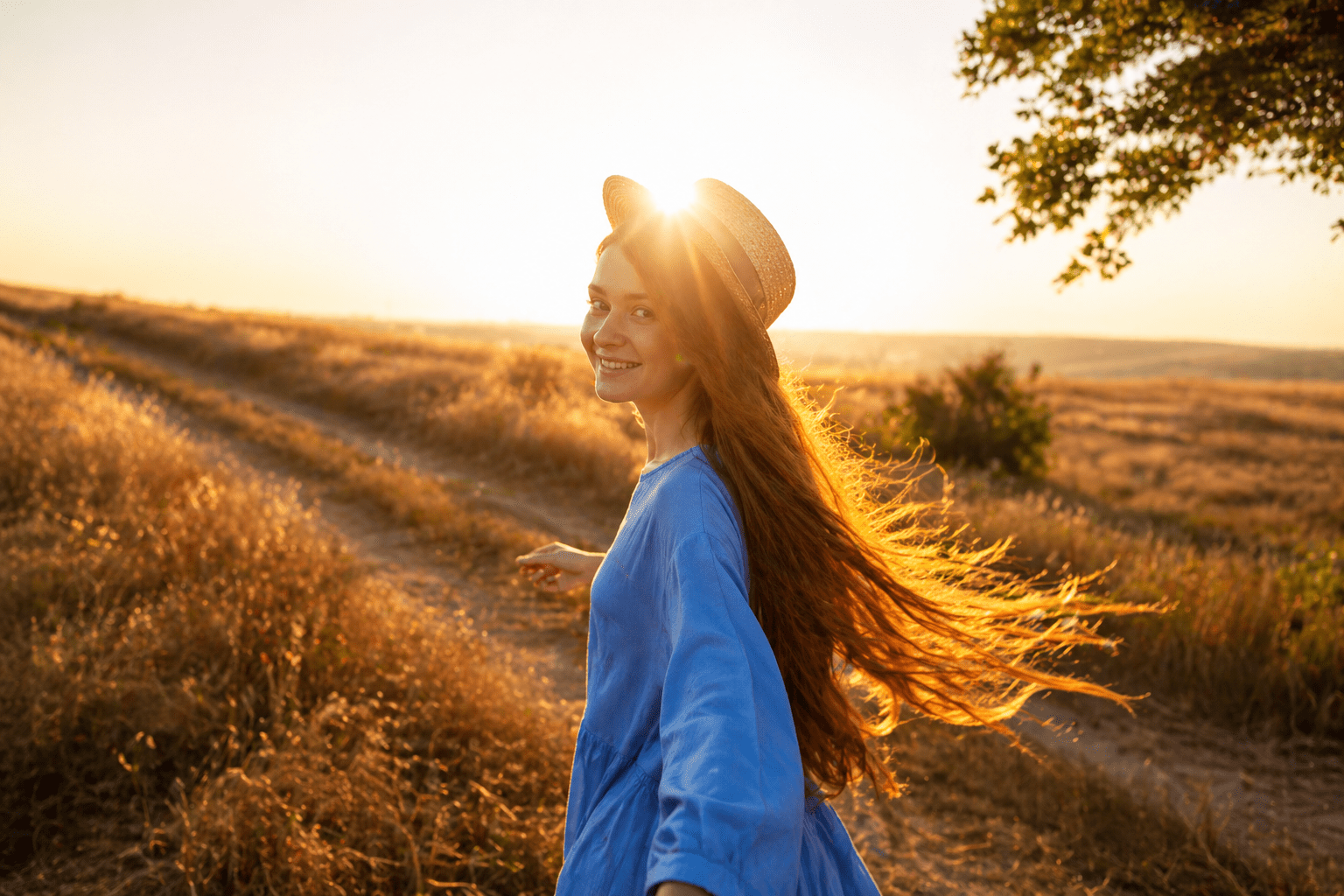 Woman in blue dress enjoying sunlit meadow breeze